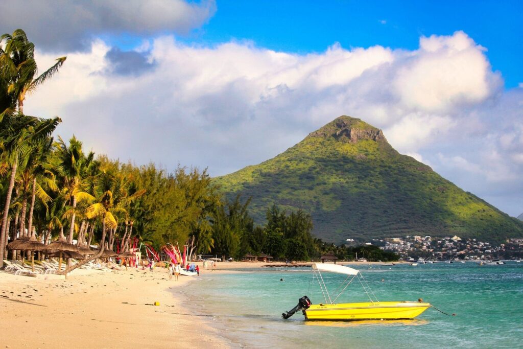 Plage de Flic en Flac avec la montagne de la Tourelle de Tamarin et un bateau jaune, côte ouest de l'île Maurice